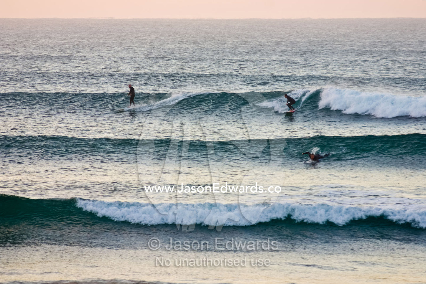 Surfers crowd the lineup as waves peel into the shore before dawn. Torquay Point, Torquay, Surf Coast, Victoria, Australia