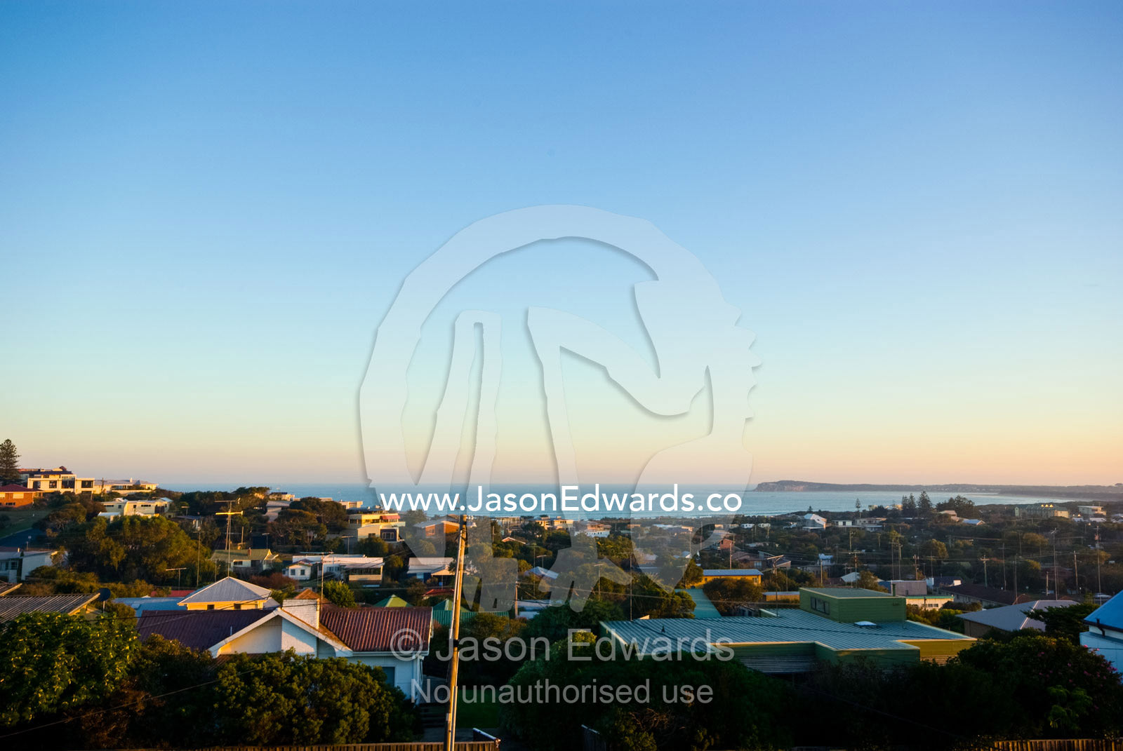 Looking to the sea over the rooftops of a coastal community at sunset. Ocean Grove, Victoria, Australia