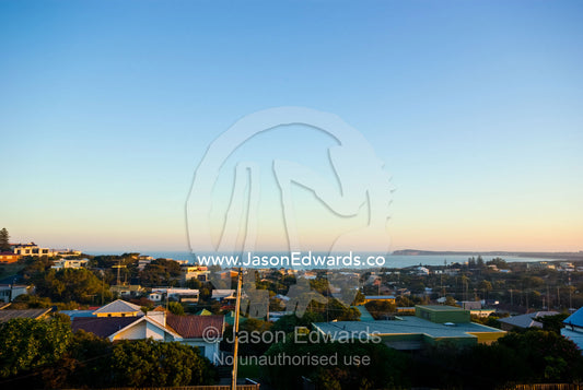 Looking to the sea over the rooftops of a coastal community at sunset. Ocean Grove, Victoria, Australia