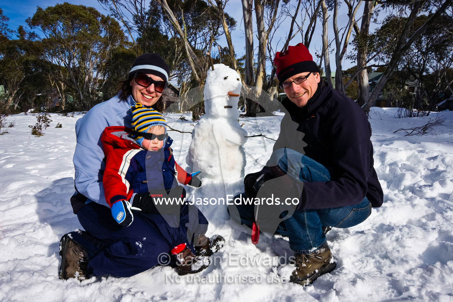 A family enjoys a fun day in the snow by building a snowman. Dinner Plain, Great Dividing Range, Victoria, Australia