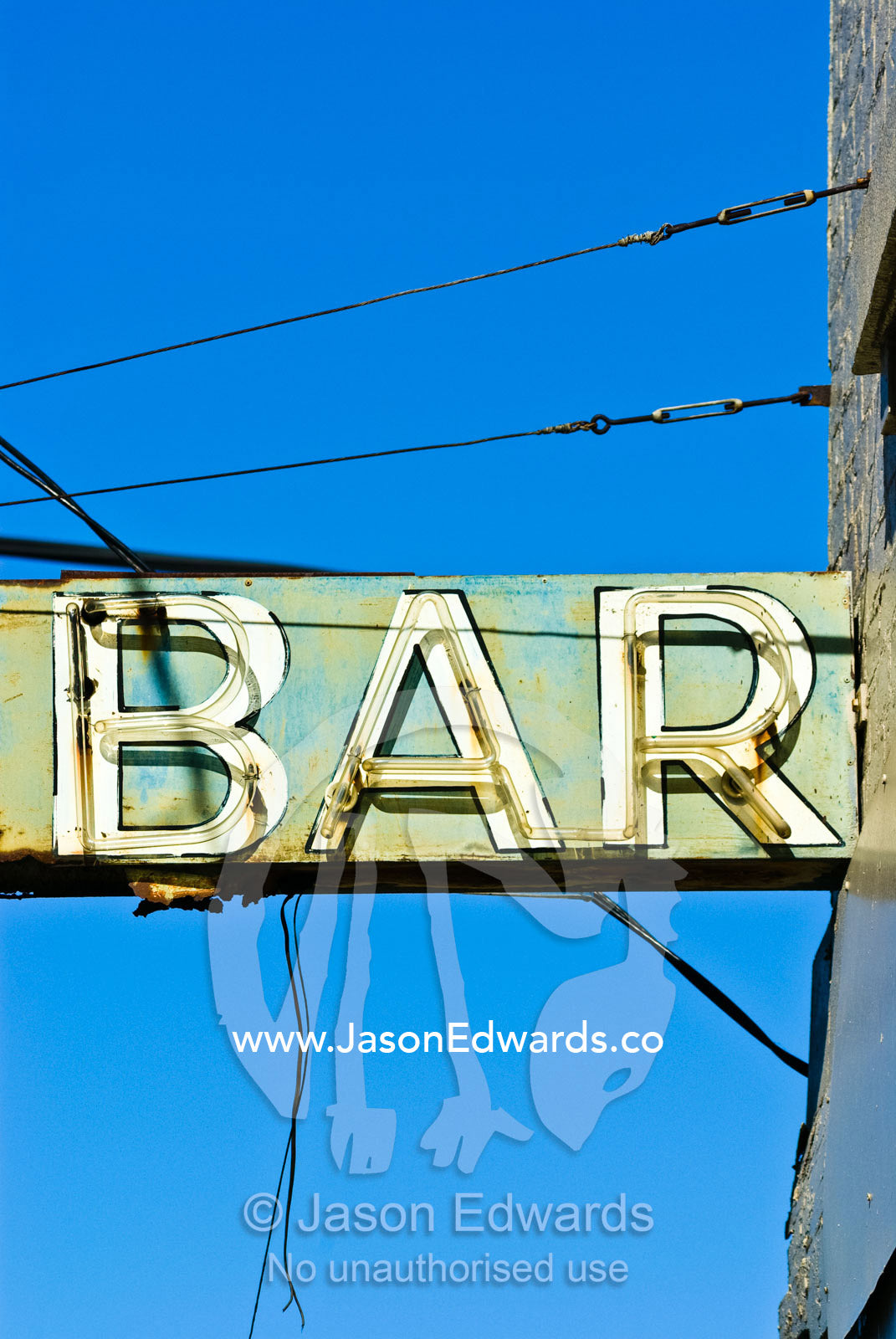 A rusting and delapidated neon bar sign surrounded by cables and wires Collingwood, Victoria, Australia