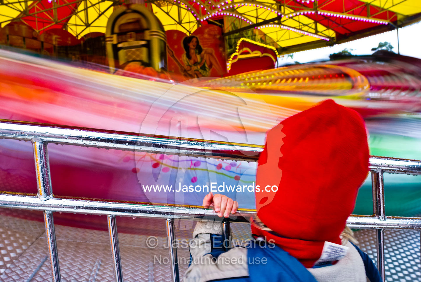 A small boy watches an amusement ride whirl by in a blur of color. Royal Melbourne Agricultural Show, Flemington, Victoria, Australia