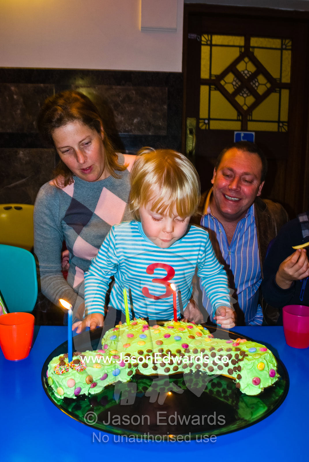 A boy celebrates his birthday by blowing out the candles on his cake. Hawthorn, Victoria, Australia