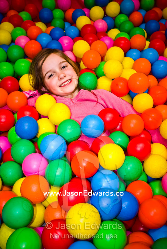 A small girl playing in a pool of colorful balls at a play center. Hawthorn, Victoria, Australia