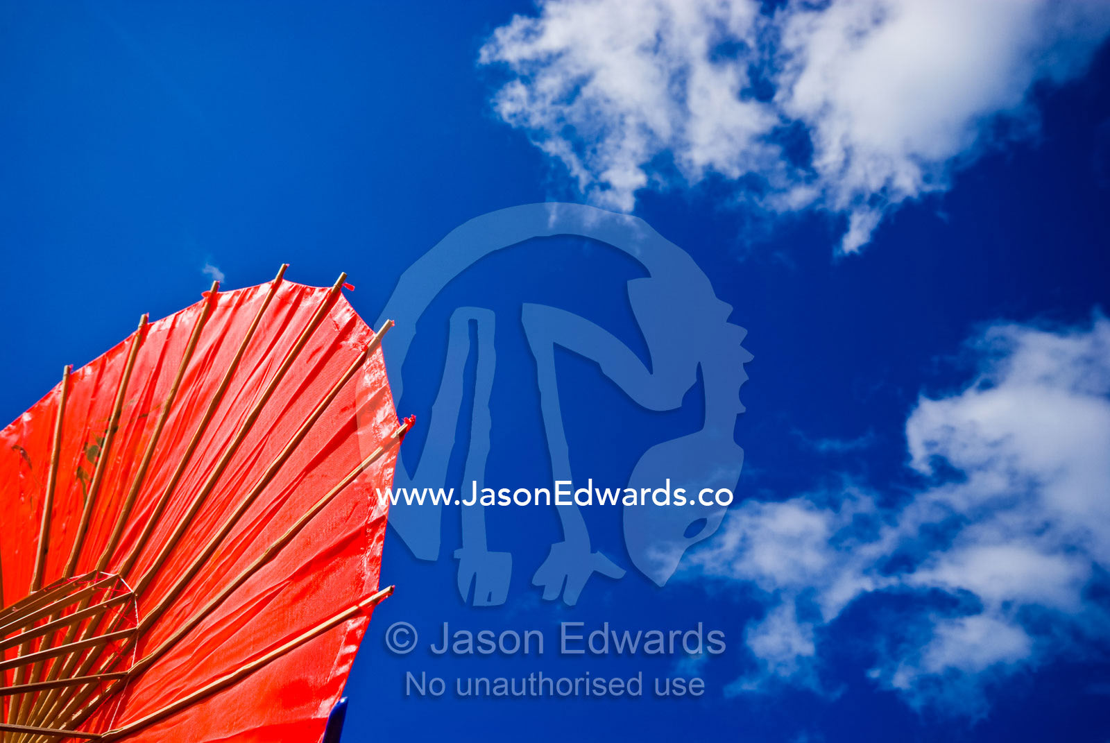 A bright red umbrella made of silk and bamboo rods at a fairground. Anglesea, Surf Coast, Victoria, Australia