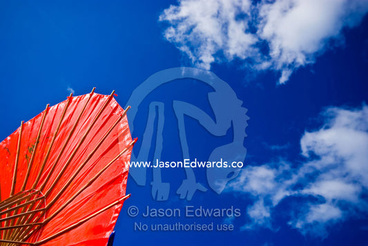 A bright red umbrella made of silk and bamboo rods at a fairground. Anglesea, Surf Coast, Victoria, Australia