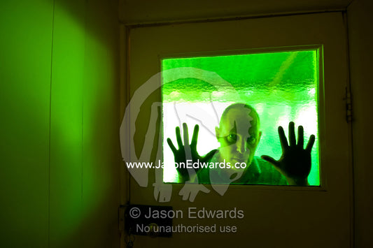 An evil-looking man peers into a house through antique green glass. Castlemaine, Victoria, Australia