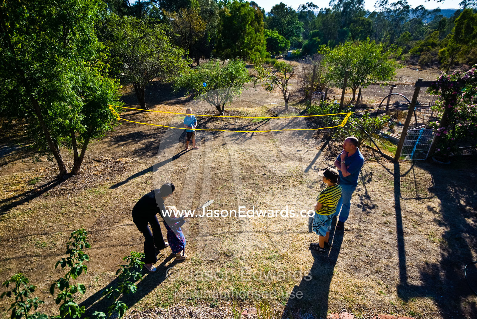 A mother teaches a child to use a racket in a game of badminton. Castlemaine, Victoria, Australia