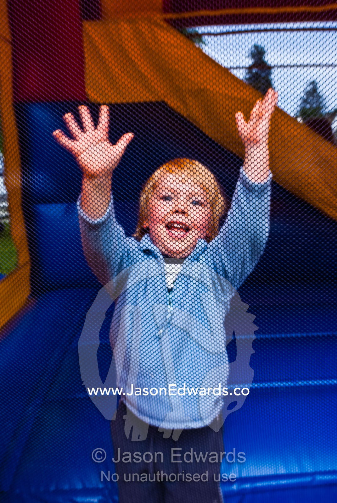 A small boy bounces inside a jumping castle at a school fair. Malvern East, Victoria, Australia