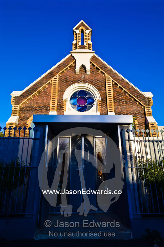 The facade and steeple of a Victorian church converted to apartments. Carlton North, Victoria, Australia