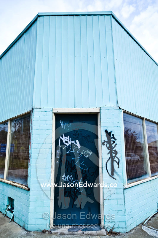Graffiti on an old corner store painted blue and turned into a house. Fitzroy North, Victoria, Australia