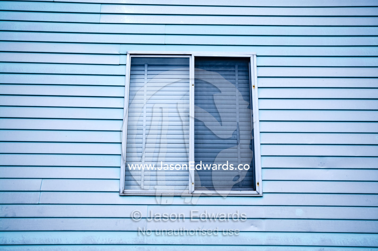 An old blue weatherboard timber wall and shuttered window of a house. Fitzroy North, Victoria, Australia