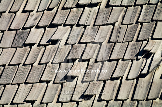 Weathered timber tiles start to lift from an old roof. Providencia District, Santiago, Chile