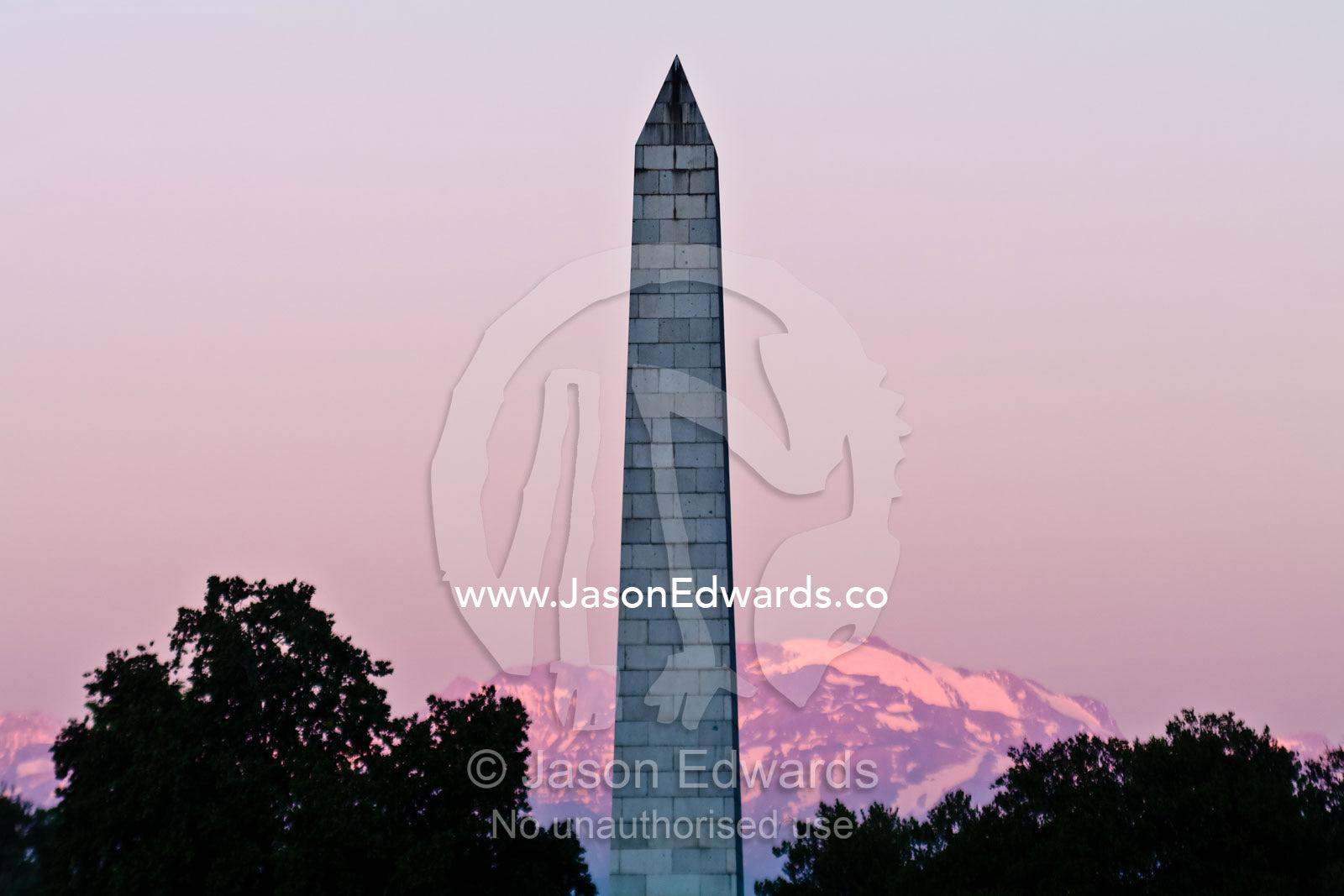 A large stone obelisk monument points into the sky at sunset. Plaza Italia, Providencia District, Maipo Valley, Andes Mountain Range, Santiago, Chile