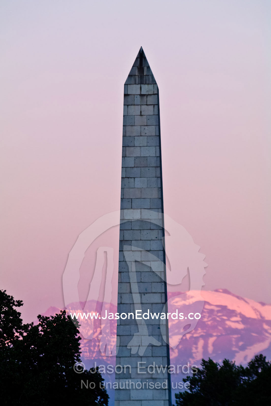 A large stone obelisk monument points into the sky at sunset. Plaza Italia, Providencia District, Maipo Valley, Andes Mountain Range, Santiago, Chile