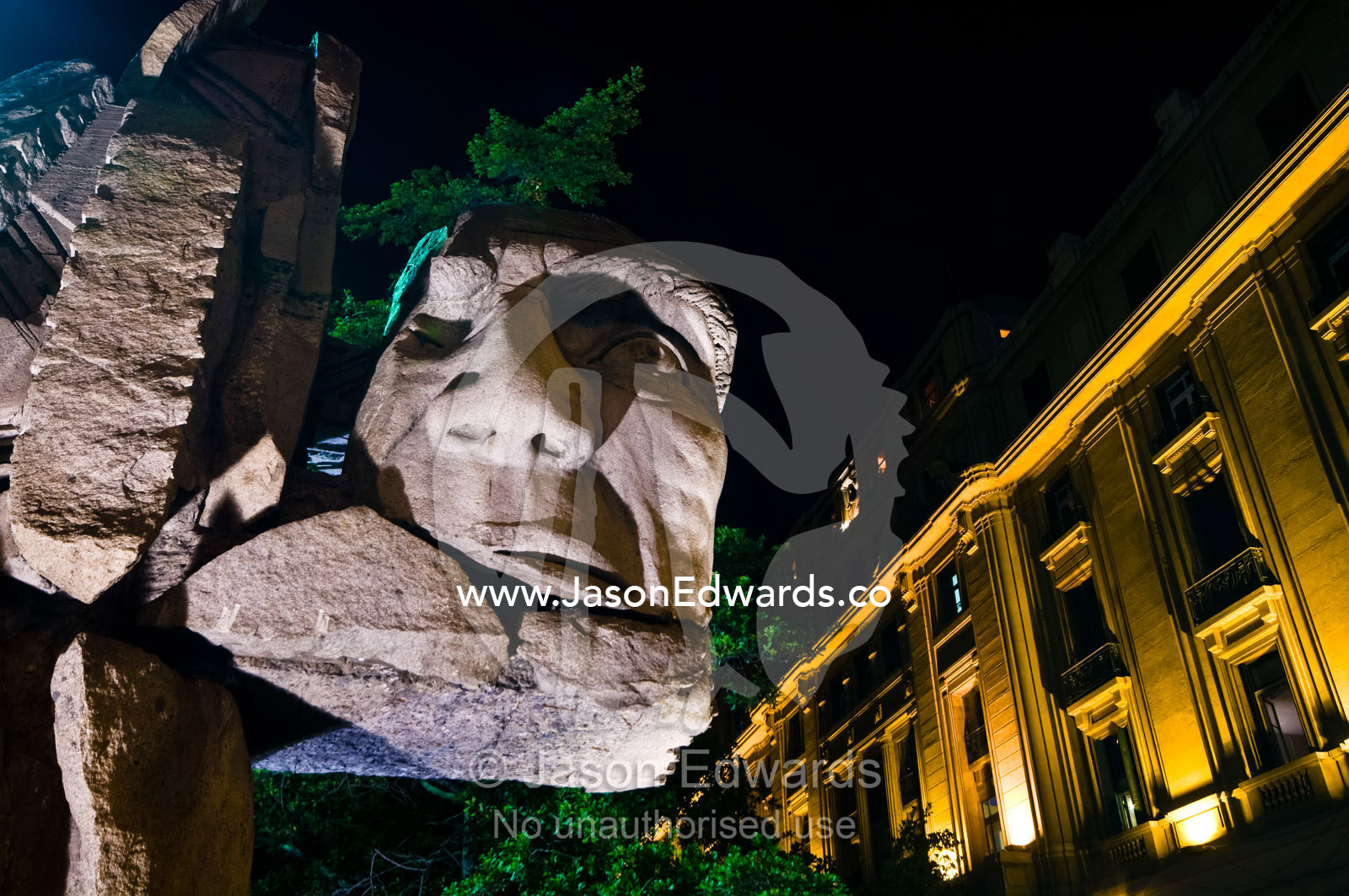 A statue featuring the face of a Latin American Indian carved in rock. Monumento Pueblo Ind��gena, Plaza de Armas, Santiago, Chile