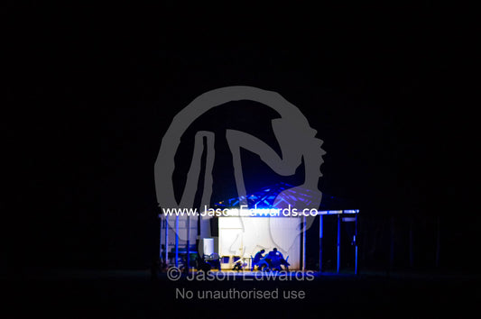 A couple prepare a meal in a shelter at a campground late at night. Batchelor, Northern Territory, Australia