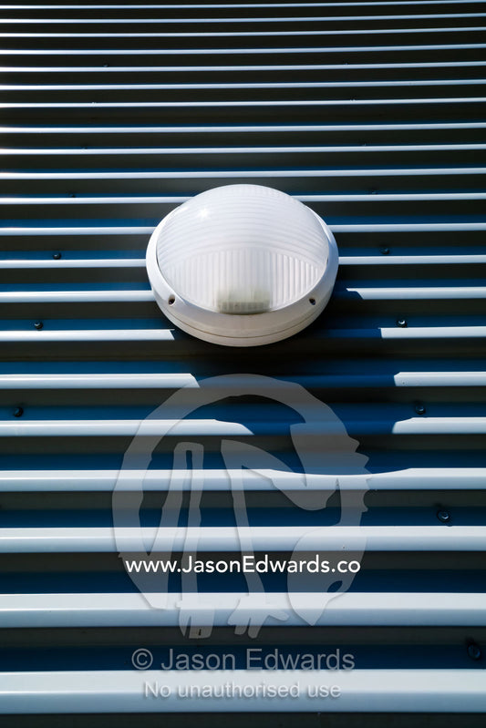 A circular plastic light bolted onto a corrugated grey steel wall. Darwin Convention Centre, Darwin, Northern Territory, Australia