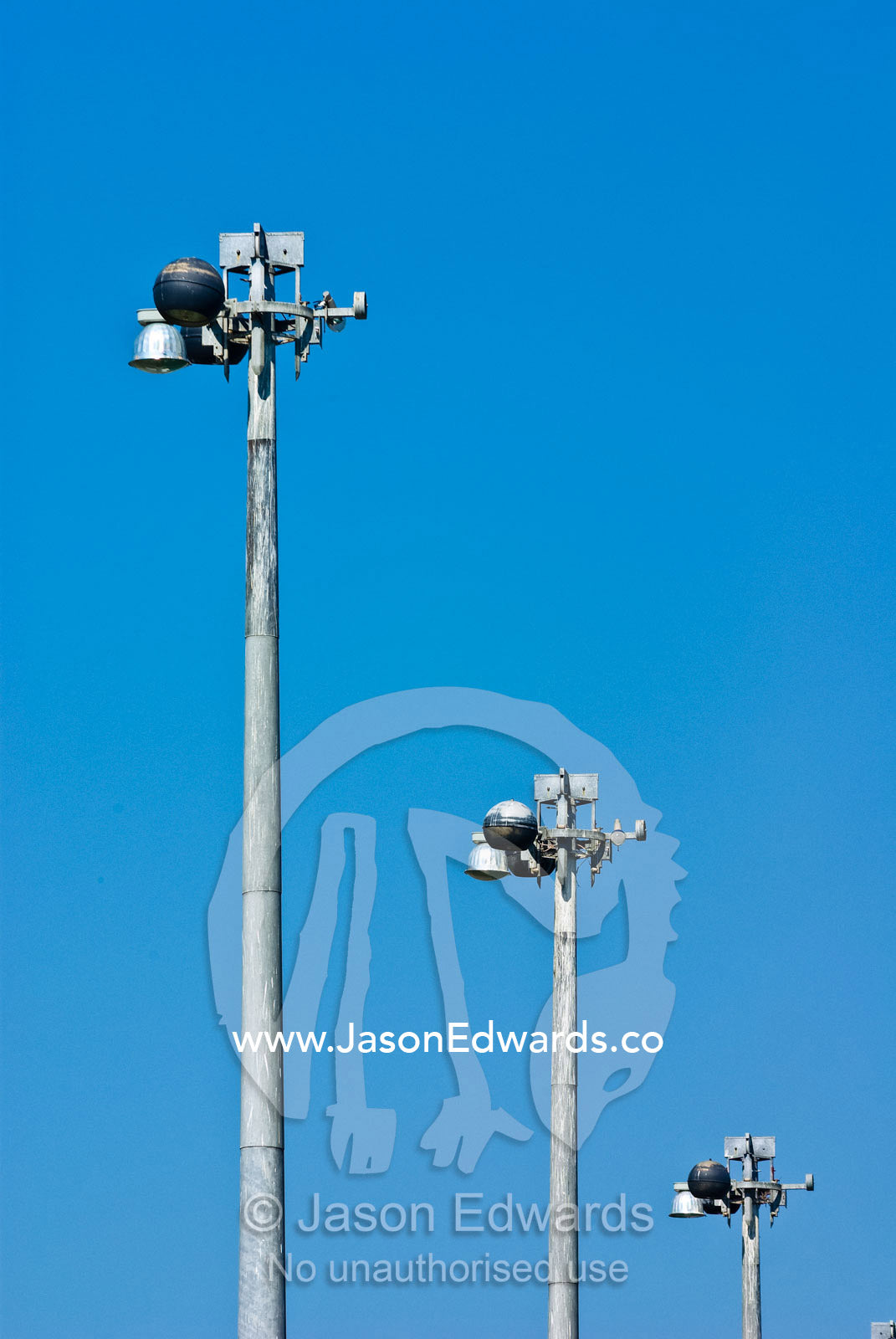 Stainless steel light poles along a marina rising into a blue sky. Darwin Waterfront, Darwin, Northern Territory, Australia
