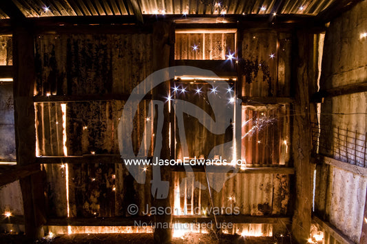 Sunlight piercing holes in a corrugated galvanized iron bakery wall. Pine Creek, Northern Territory, Australia