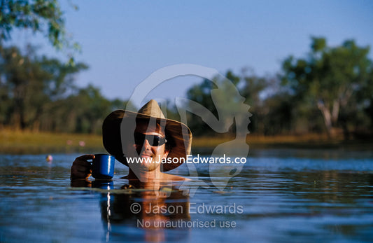 A National Park ranger cools off with a drink in an outback billabong. Limmen National Park, Gulf of Carpentaria, Northern Territory, Australia