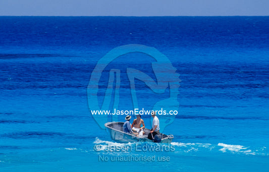 A group of men on a tropical turquoise ocean in an aluminium dingy. Coral Sea, Queensland, Australia