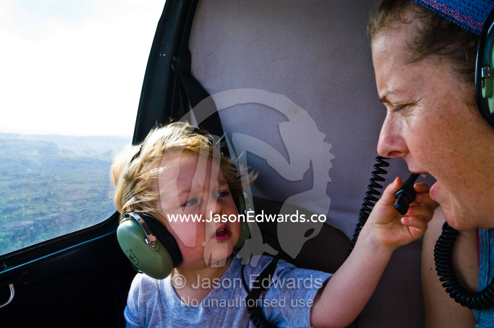 A small boy and his mother communicate via headphones in a helicopter. Kakadu National Park, Northern Territory, Australia.