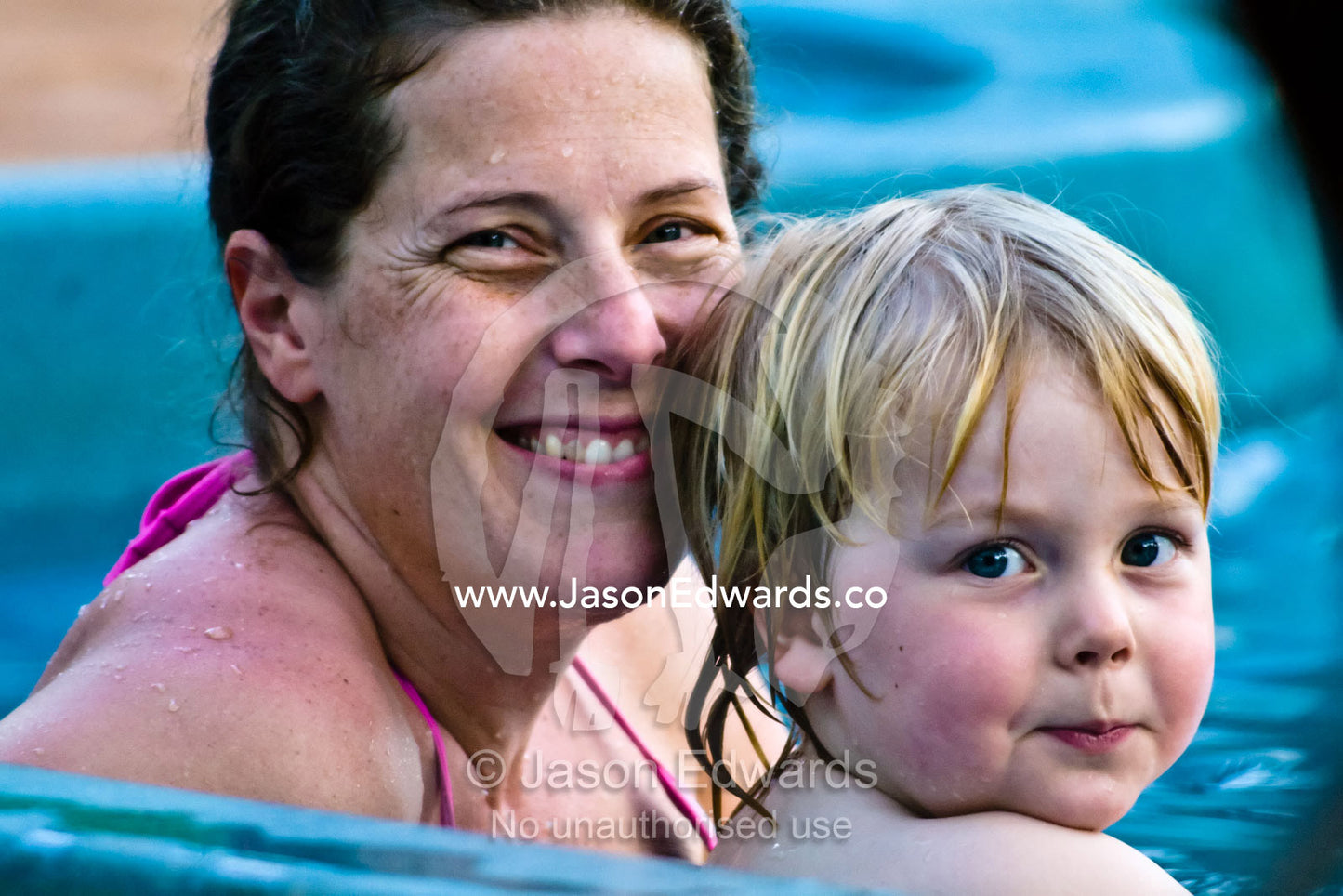 A mother and her small blonde son cooling off in a swimming pool. Batchelor, Northern Territory, Australia.