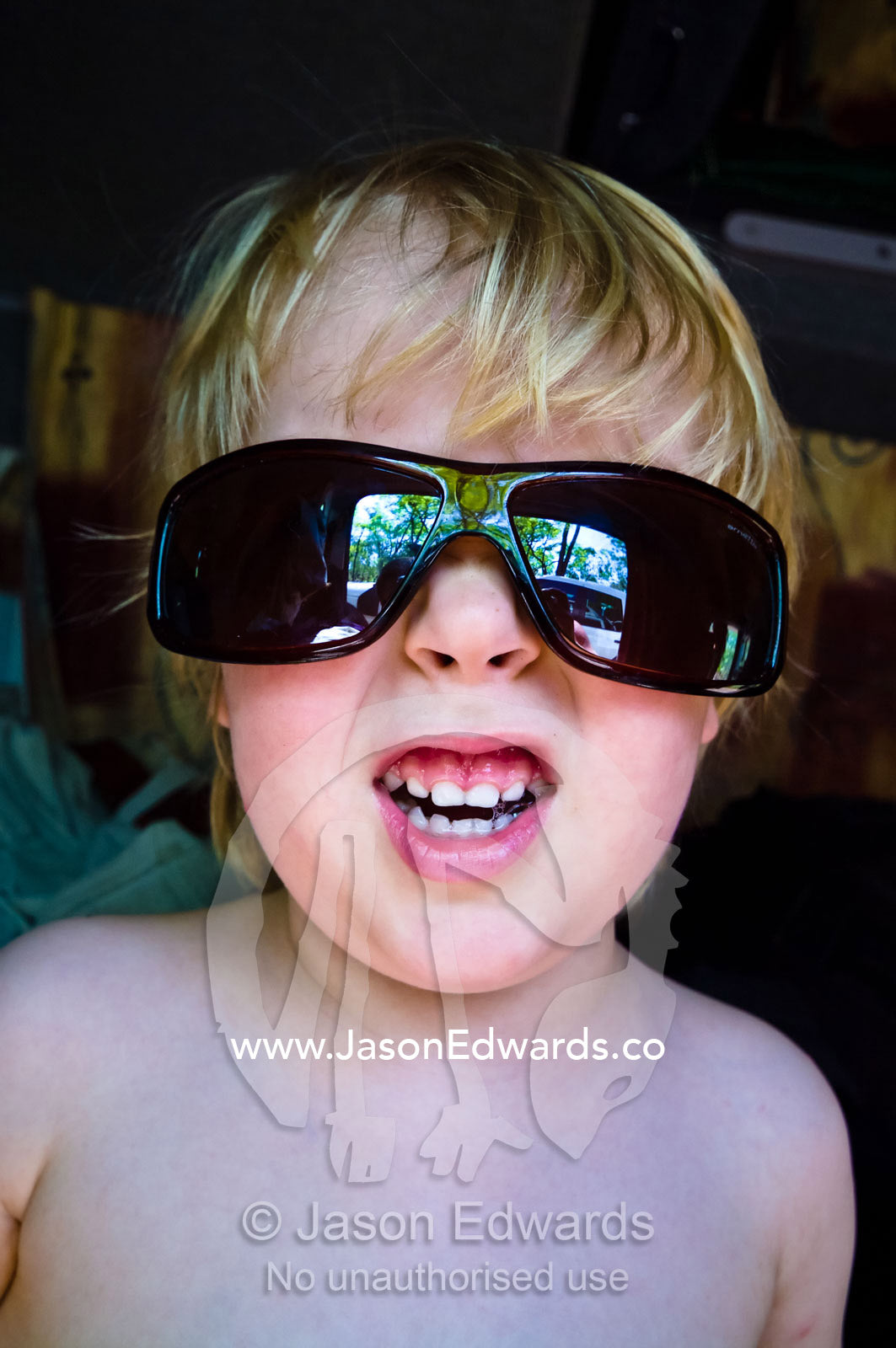 A fair-skinned, blonde boy wearing sunglasses snarls at the camera. Buley, Rockhole, Litchfield National Park, Northern Territory, Australia.
