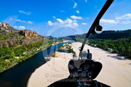 The view through a helicopter cockpit as it flies over a remote river. East Alligator River, Arnhem Land Border, Kakadu National Park, Northern Territory, Australia
