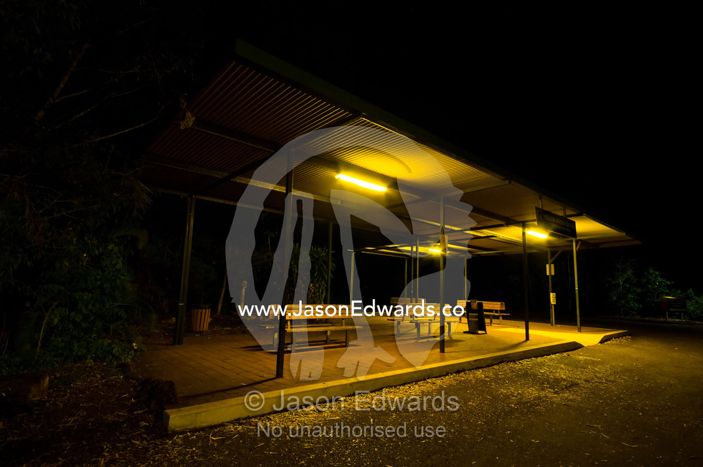 Fluorescent lights cast an eerie glow over an empty bus stop at night. Gagudju Cooinda Lodge, Yellow Water, Kakadu National Park, Northern Territory, Australia.