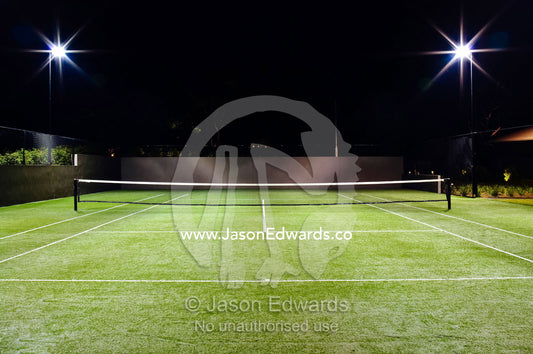 Floodlights illuminate a private tennis court on a wealthy homestead. Red Hill, Mornington Peninsula, Victoria, Australia.