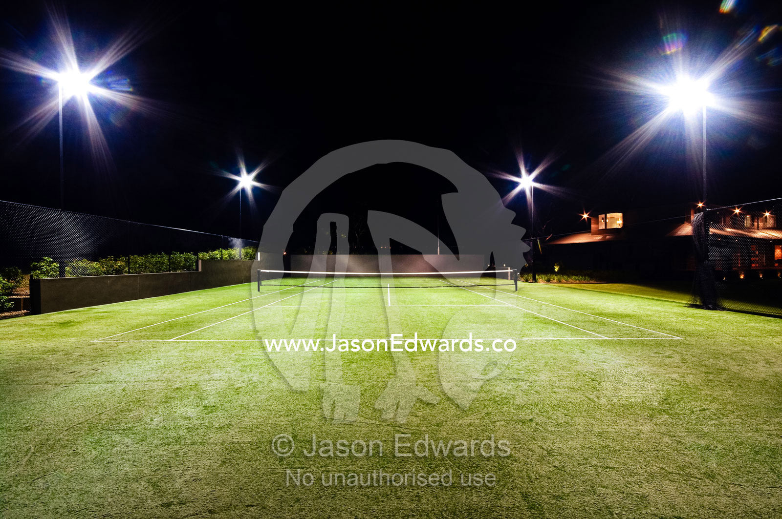 Floodlights illuminate a private tennis court on a wealthy homestead. Red Hill, Mornington Peninsula, Victoria, Australia.