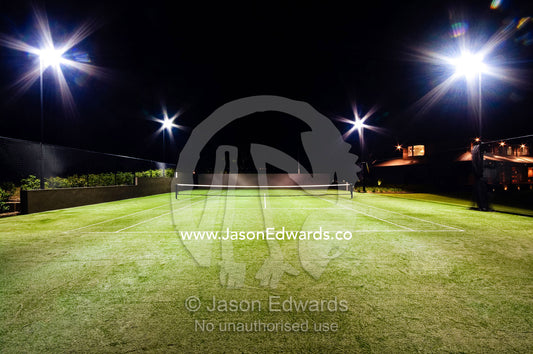 Floodlights illuminate a private tennis court on a wealthy homestead. Red Hill, Mornington Peninsula, Victoria, Australia.