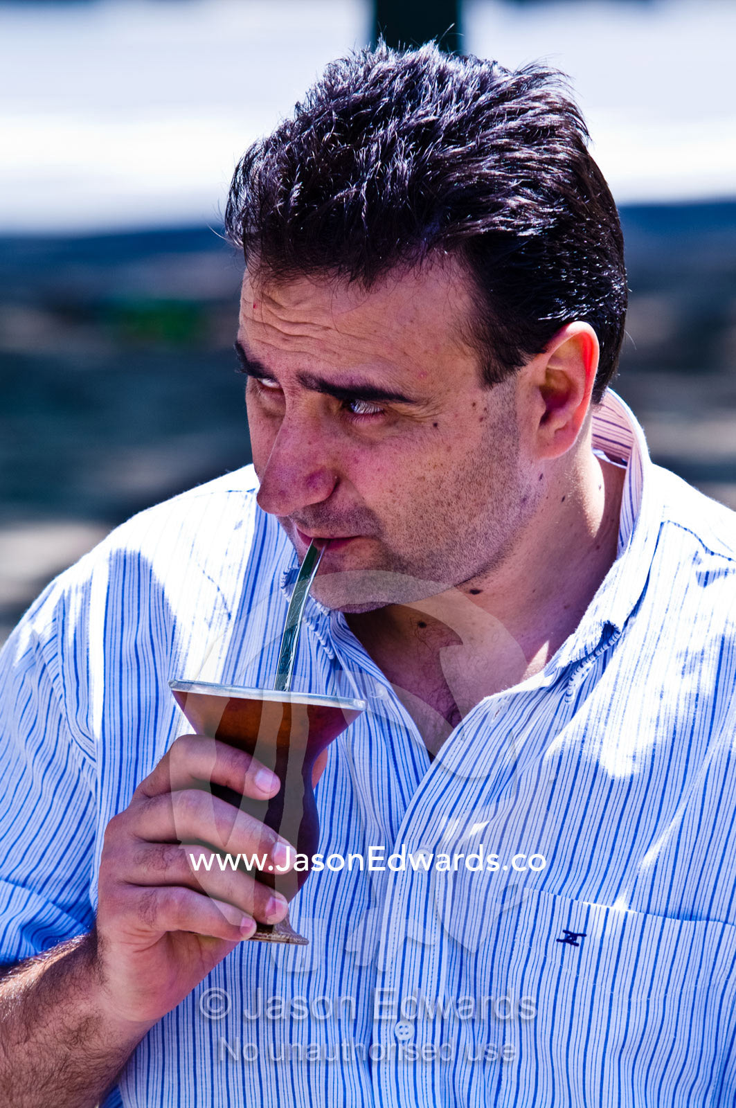 A man enjoys drinking mate from a silver straw known as a bombilla. Plaza Eva Peron, Avenue Perseo Colon, San Telmo, Buenos Aires, Argentina.
