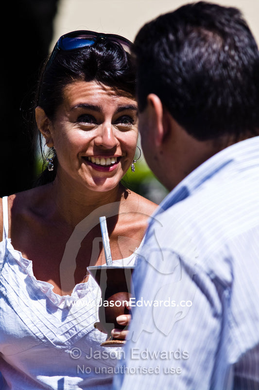 A lady enjoys drinking mate from a silver straw known as a bombilla. Plaza Eva Peron, Avenue Perseo Colon, San Telmo, Buenos Aires, Argentina.