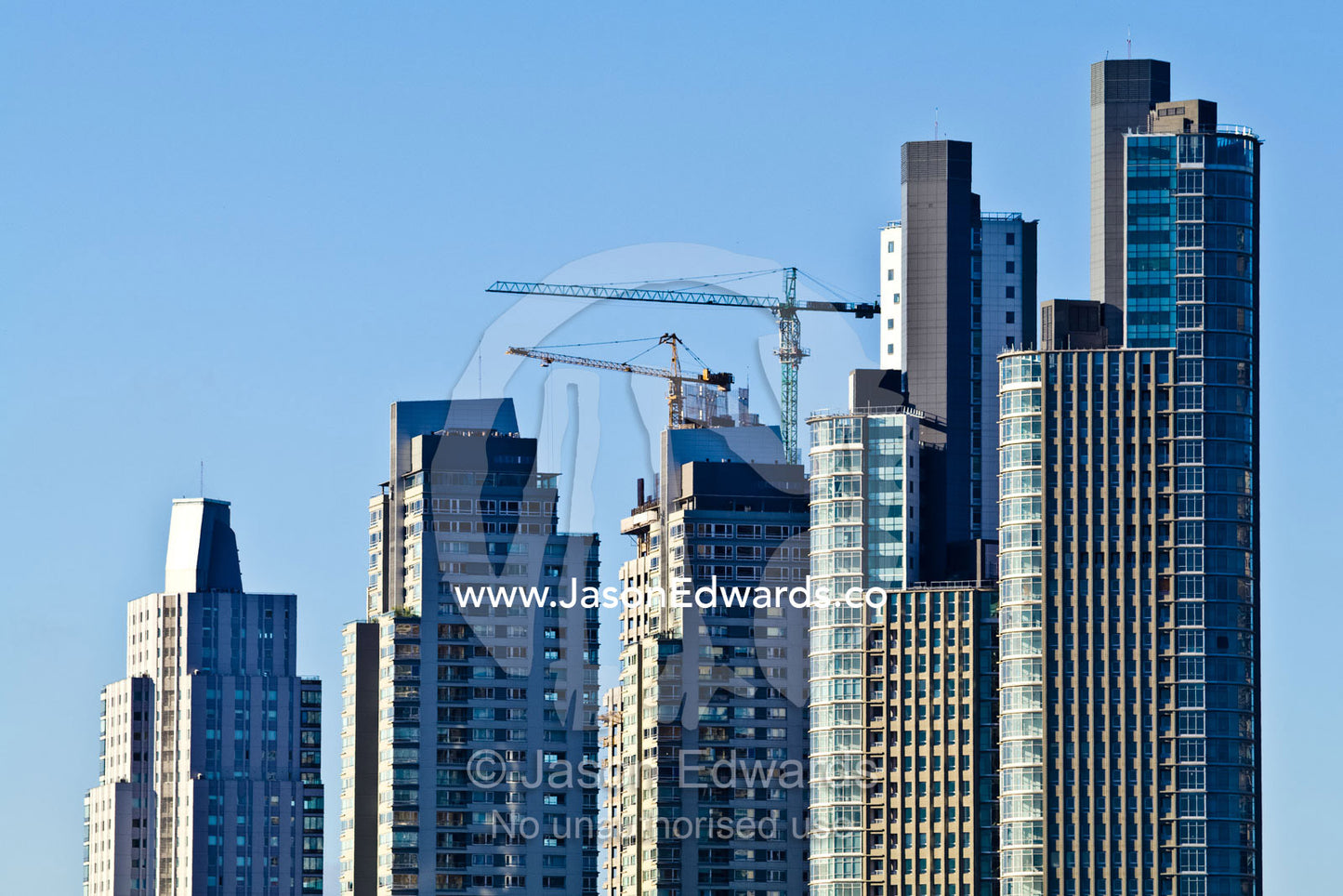 Cranes and construction emerge from buildings in a new city skyline. Puerto Madero, Buenos Aires, Argentina.