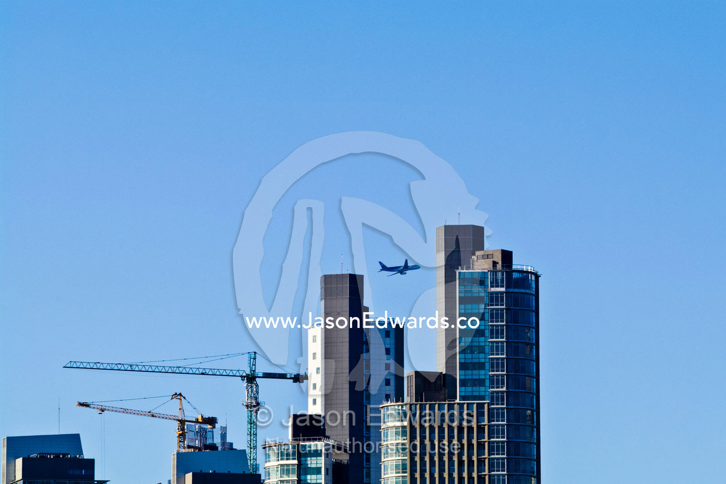 A passenger airline flies over a new city skyline under construction. Puerto Madero, Buenos Aires, Argentina.