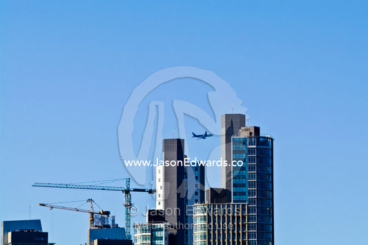 A passenger airline flies over a new city skyline under construction. Puerto Madero, Buenos Aires, Argentina.