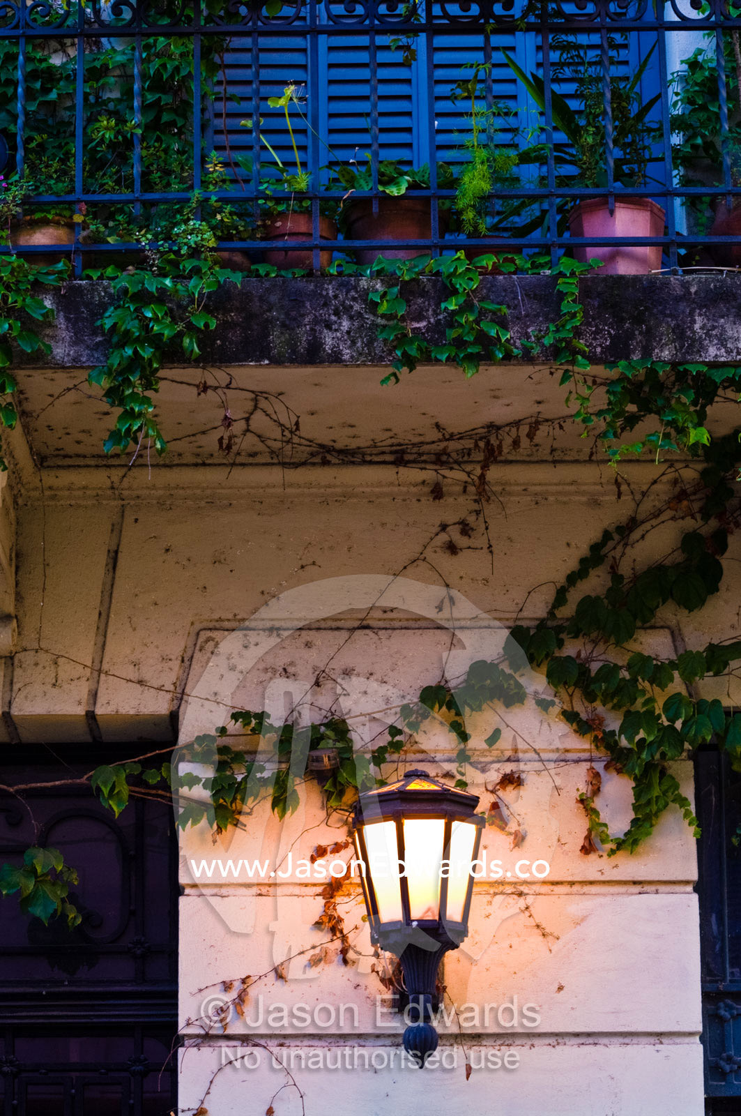 An antique wall lamp beneath a small vine-covered balcony garden. San Telmo, Buenos Aires, Argentina.