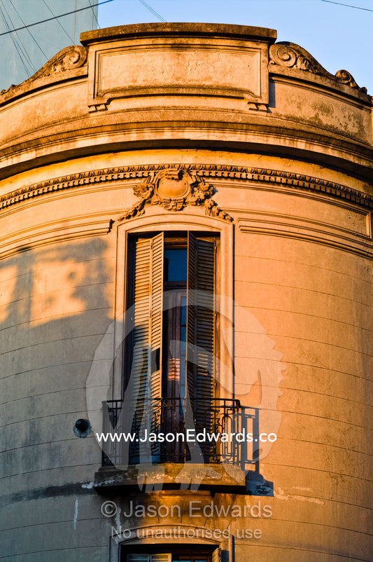 Sunset illuminates an ornate apartment balcony and shuttered windows. San Telmo, Buenos Aires, Argentina.