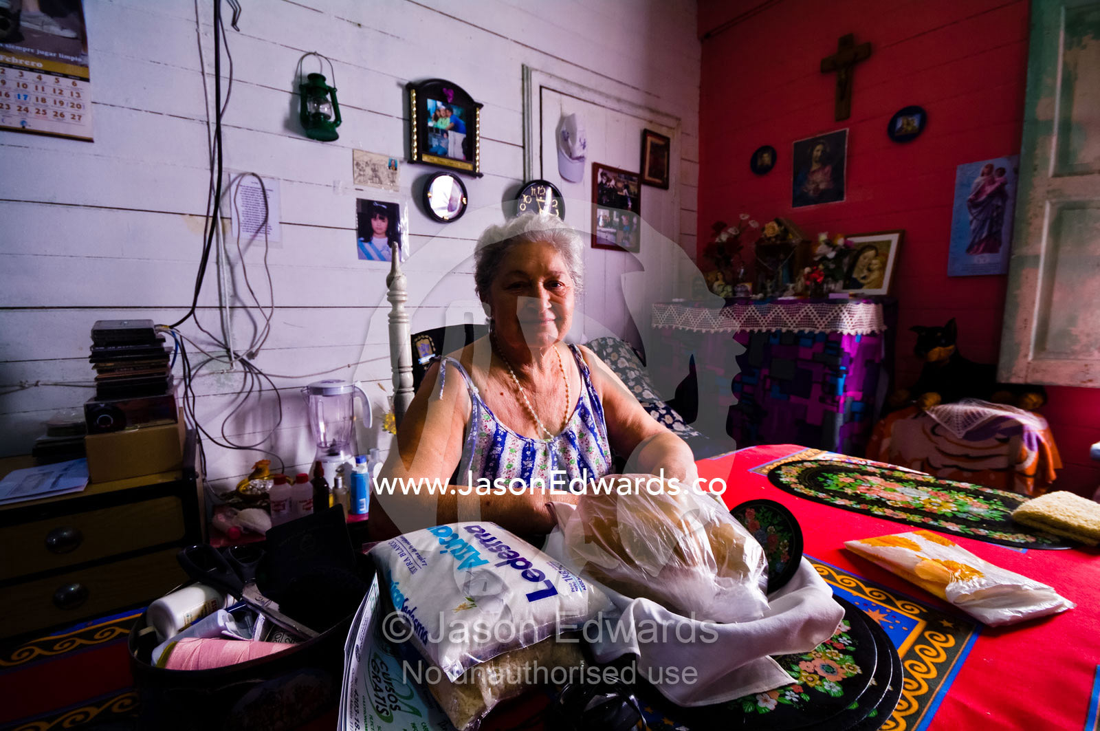 Religious artifacts surround an elderly lady in her colorful home. La Boca, Buenos Aires, Argentina