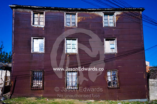 A rusting corrugated tin conventillo houses several poor families. La Boca, Buenos Aires, Argentina.