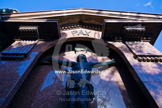 A statue of Christ on the facade of a mausoleum in a city cemetery. La Recoleta Cemetery, Recoleta, Buenos Aires, Argentina.