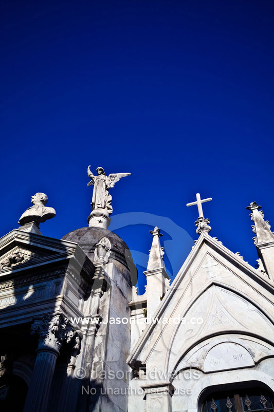 Concrete statues of an angel and crucifix on the roof of a mausoleum. La Recoleta Cemetery, Recoleta, Buenos Aires, Argentina