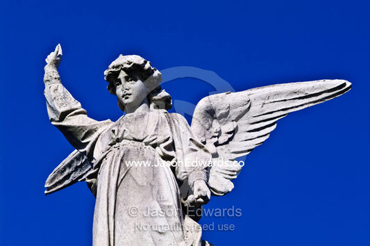 A concrete statue of an angel on the roof of a family mausoleum. La Recoleta Cemetery, Recoleta, Buenos Aires, Argentina.