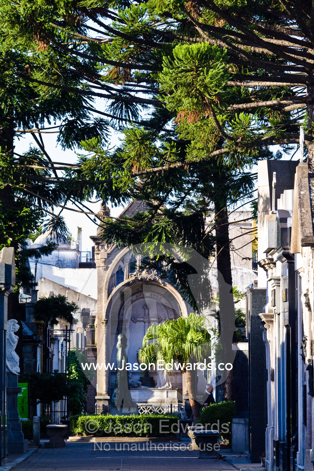 Large trees and gardens surround family mausoleums in a city cemetery. La Recoleta Cemetery, Recoleta, Buenos Aires, Argentina.