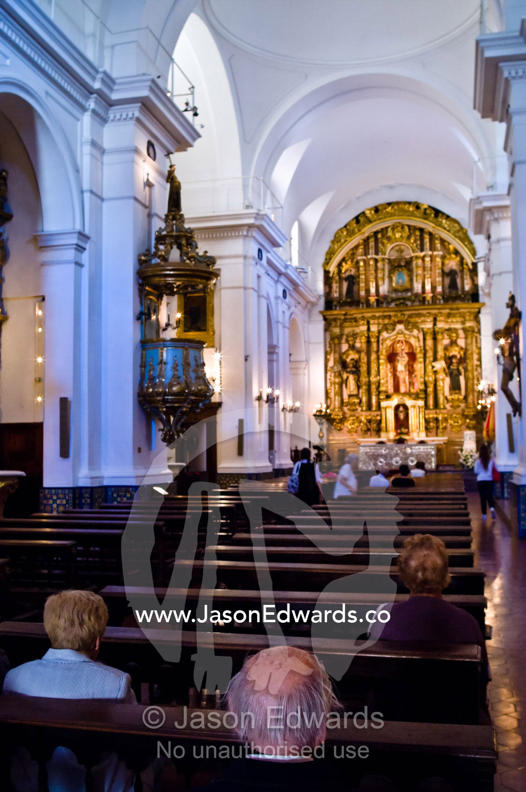 The nave, pews, aisle, and clerestory windows of an ornate church. Our Lady of Pilar Basilica, Recoleta, Buenos Aires, Argentina.