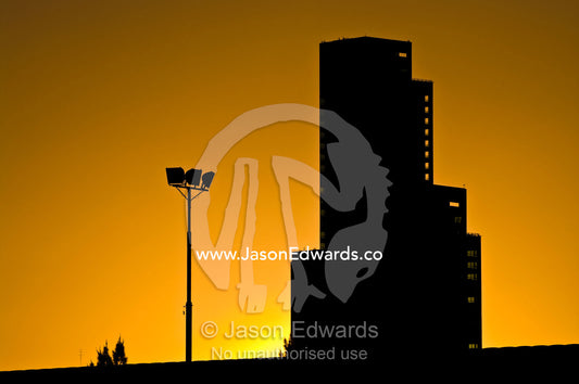 A large monolithic building and floodlights silhouetted at sunset. near Estacion Retiro, Retiro Railway Station, Buenos Aires, Argentina.