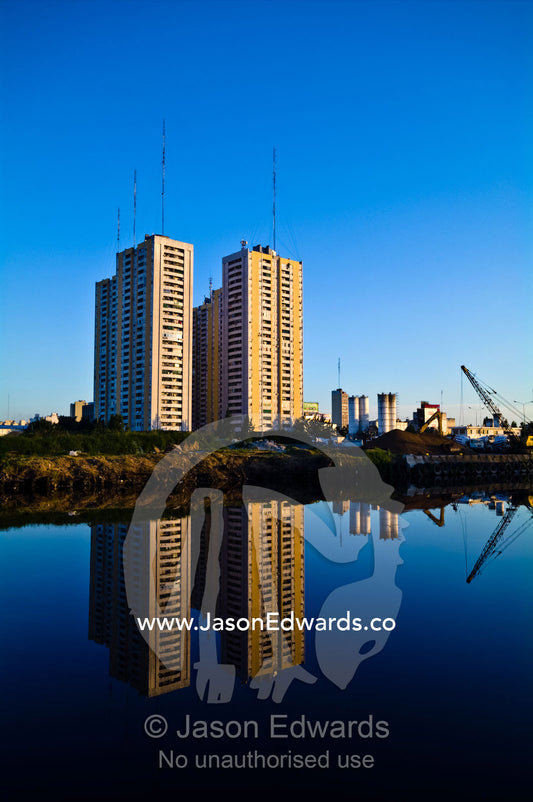 Low income apartment blocks reflected on the still surface of a river. Riachuelo River, La Boca, Buenos Aires, Argentina.